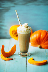 Pumpkin smoothie, spice latte with whipped cream on top on a turquoise wooden background. copy space