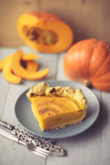 Traditional pumpkin pie preparation with filling, dough and ingredients on dark rustic background, top view, retro styled, frame