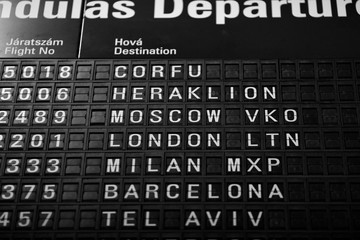 Obraz premium Departures board at the airport. Flight information mechanical timetable. Split flap mechanical departures board. Flight schedule