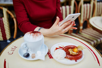 Obraz na płótnie Canvas Woman's hands with mobile phone, cup of coffee and cake