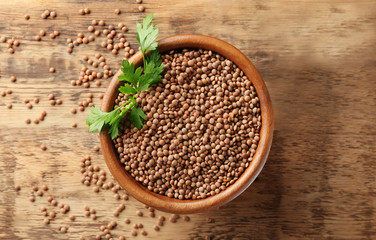 Bowl with brown lentils on wooden background