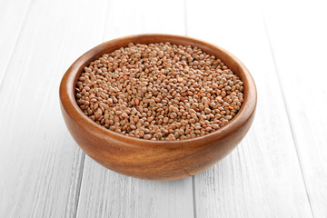 Bowl with brown lentils on wooden background