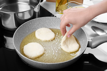 Woman frying pancakes in kitchen