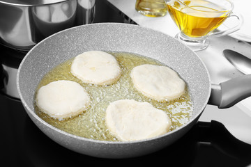 Frying pan with raw pancakes in kitchen