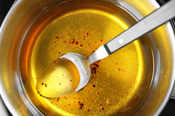Saucepan with used vegetable oil and spoon, closeup