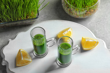 Wheat grass shots and slices of lemon on white board