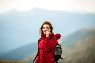 Happy young blonde woman portrait. Girl tourist in mountain. Shot of a young woman looking at the landscape while hiking in the mountains. Travel inspiration and motivation, beautiful landscape