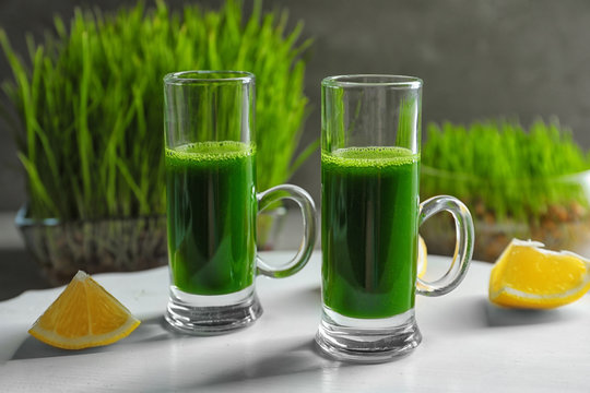 Wheat grass shots and slices of lemon on white board
