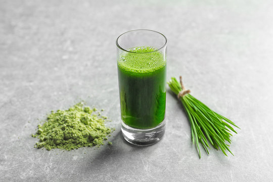 Wheat grass shot and powder on grey background