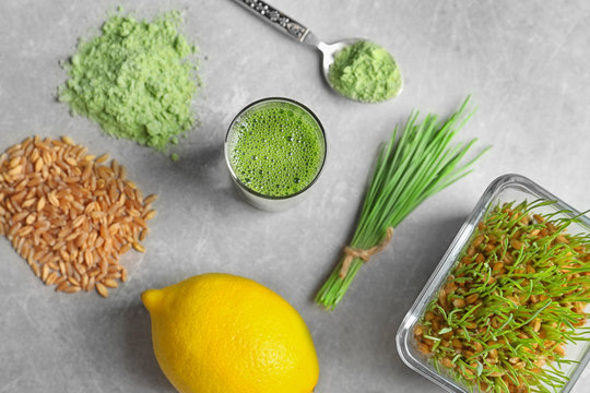 Composition with wheat grass products and lemon on grey background