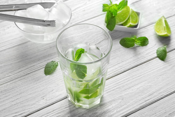 Glass with mint, ice and lime slices on table