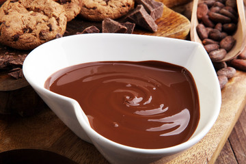 Chocolate cream melted and chocolate pieces on wooden table