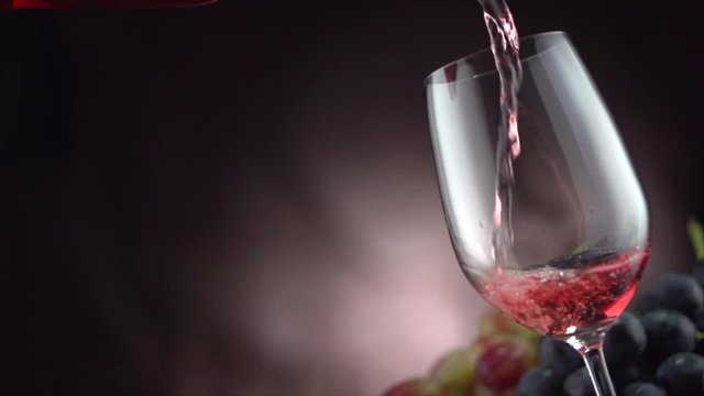 Wine. Red wine pouring in wine glass over dark background. Slow motion. Full HD video 1920X1080