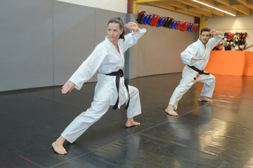 man and woman in white kimono black belt training karate