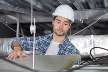 electrician fixes halogen lamp in ceiling light in room