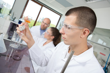 Student scientist pouring chemical into beaker