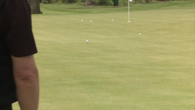 Chipping onto a golf practice green using aiming rods