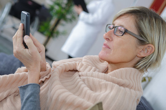 Woman In Hospital Waiting Room Using Her Phone