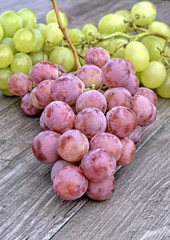 Ripe white and red grapes on a wooden background.