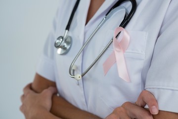 Mid section of female doctor with Breast Cancer Awareness ribbon