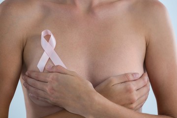 Mid section of woman with  Breast Cancer Awareness ribbon