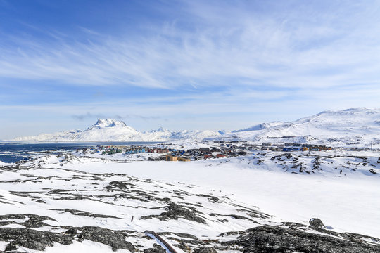 Nuuk city suburb at the fjord, snow landscape with blue sky and Sermitsiaq mountain in the background, Greenland