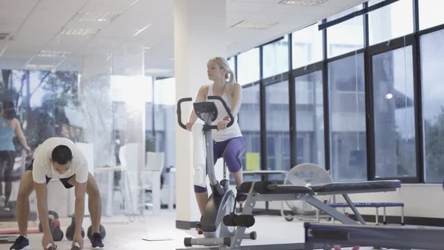 Fit group working out in the gym, video screen showing moving outdoor scene