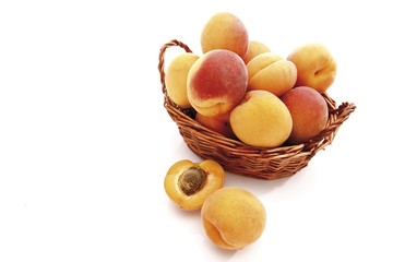 Apricots (Prunus armeniaca) in a small basket, with one cut in half laying in front