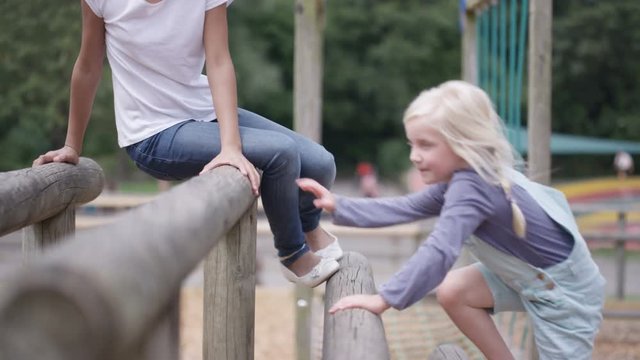  Little girls playing on climbing bars in adventure playground