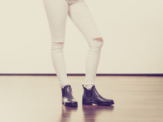 Woman legs in trousers with holes and black boots
