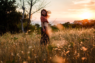 Young woman relaxing in summer sunset sky outdoor hair develops  in a radiant field. People freedom...