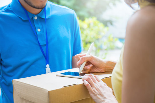 woman accepting receive a delivery of boxes from delivery asian man, sign and receive delivery concept 