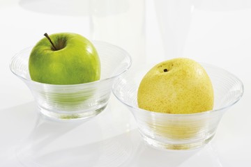 Green apple and a nashi pear in glass bowls