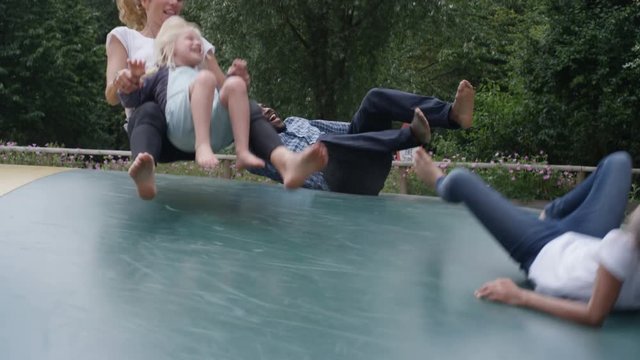  Happy mixed race family having fun, jumping on inflatable at activity centre