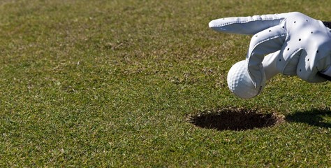 Putting without golf clubs, hand holding a golf ball