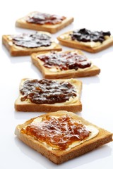 Six slices of toast with various jams, rhubarb jam, apricot jam, strawberry jam, orange marmalade, cherry jam and ginger marmalade