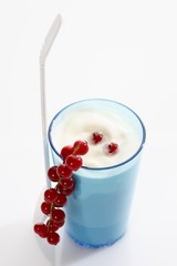 Blue cup and white plastic spoon with yoghurt and red currants