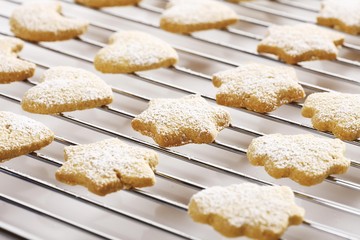Shortcrust cookies on oven grid, dusted with powdered sugar