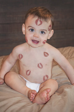 Baby with lipstick kisses on body skin 