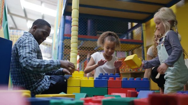 Happy mixed race family having fun with building bricks at indoor playground