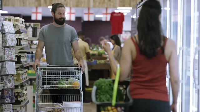  Man & woman flirting exchange glances as they're shopping in grocery store