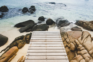 Wood bridge on the beach with rock and ocean view in Koh Munnork island, Thailand.