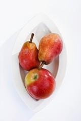 Red apple and two red pears on a plate