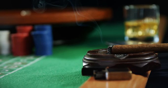Casino chips, cigar and glass of beer on poker table 
