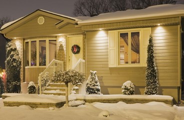 Bungalow style residential home illuminated in winter at dusk with Christmas decorations, Quebec,...