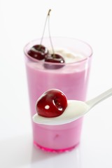 Pink cup and white plastic spoon with yoghurt and cherries