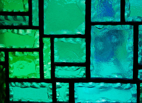 Ausschnitt aus einem geometrischen Buntglasfenster in Grün- und Blautönen