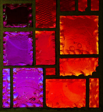 Ausschnitt aus einem geometrischen Buntglasfenster in Rot- und Violetttönen