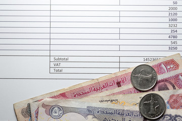 UAE dirhams banknotes and coins on a invoice with VAT box. UAE will implement VAT at the rate of 5% on 1 January 2018.