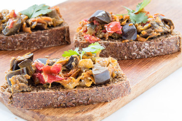 sandwiches with eggplant caviar and coriander leaves on wooden board, close-up